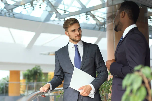 Twee multinationale jonge ondernemers bespreken van zaken tijdens de bijeenkomst in kantoor. — Stockfoto