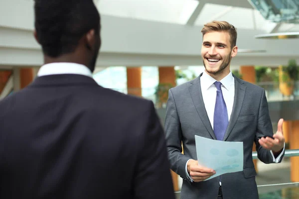 Twee multinationale jonge ondernemers bespreken van zaken tijdens de bijeenkomst in kantoor. — Stockfoto