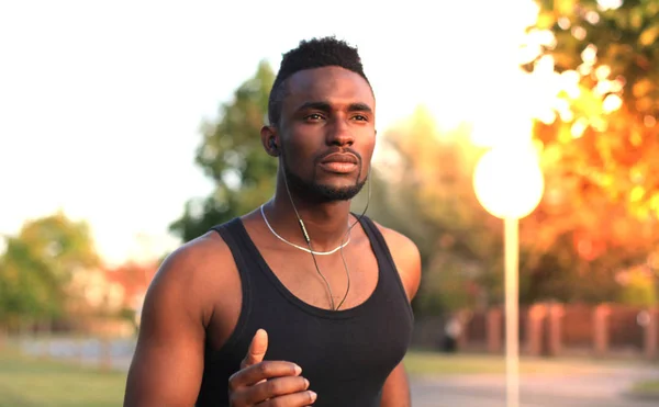 Hombre africano con ropa deportiva corriendo mientras hace ejercicio al aire libre, al atardecer o al amanecer. Corredor . —  Fotos de Stock