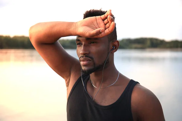 Hombre africano con ropa deportiva corriendo mientras hace ejercicio, en el retrato al aire libre de la playa, al atardecer o al amanecer. Corredor . —  Fotos de Stock