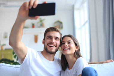 Genç çift evde oturma odasında kanepede bir selfie alarak.