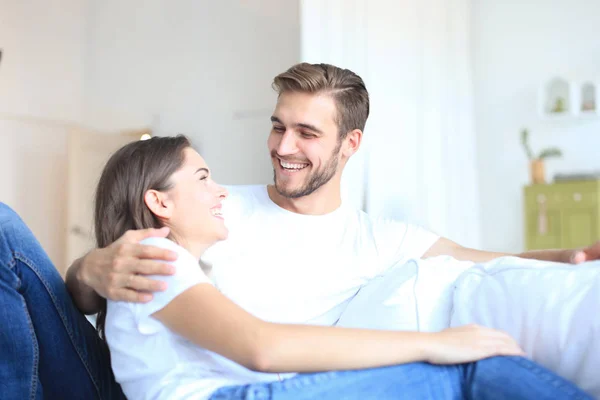 Feliz pareja joven abrazándose y disfrutando en un sofá en casa . —  Fotos de Stock