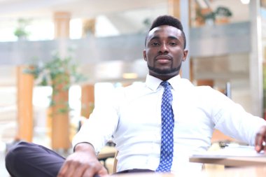 Office işyerinde kameraya bakarak mutlu genç Afrikalı-Amerikalı iş adamı.