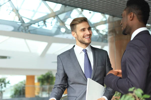 Два многонациональных молодых бизнесмена обсуждают бизнес на встрече в офисе . — стоковое фото