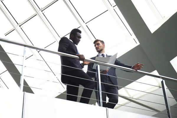 Вид снизу. Два многонациональных молодых бизнесмена обсуждают в офисе во время деловой встречи . — стоковое фото