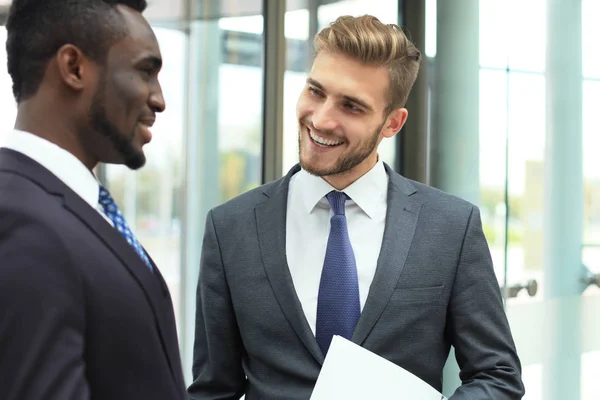 Två multinationella unga affärsmän diskuterar verksamheten vid möte i office. — Stockfoto