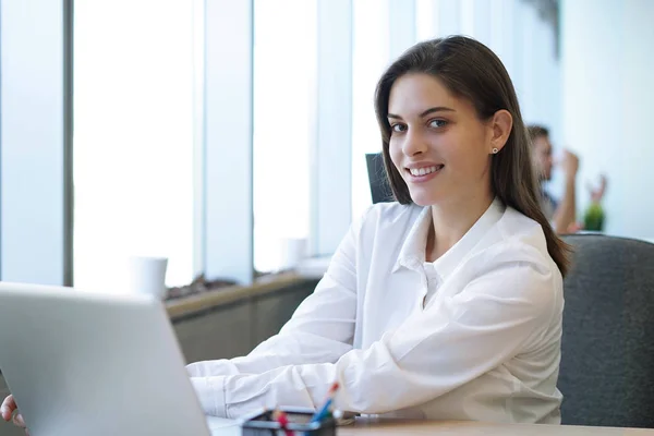 Mooie zakenvrouw is op zoek naar camera en glimlachen tijdens het werken in het kantoor. — Stockfoto
