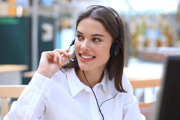 Operadora de suporte ao cliente feminina com fone de ouvido e sorrindo. — Fotografia de Stock