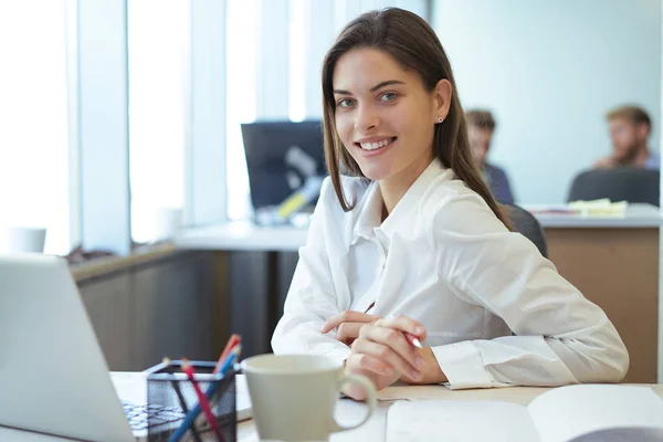 Belle dame d'affaires regarde la caméra et souriant tout en travaillant dans le bureau. — Photo