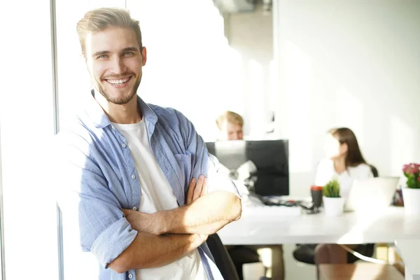 Porträtt av en lycklig ung casual affärsman på kontor, leende. — Stockfoto