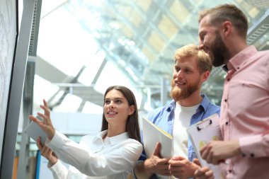 Beyaz tahta ofisteki çalımakta rahat iş adamları.