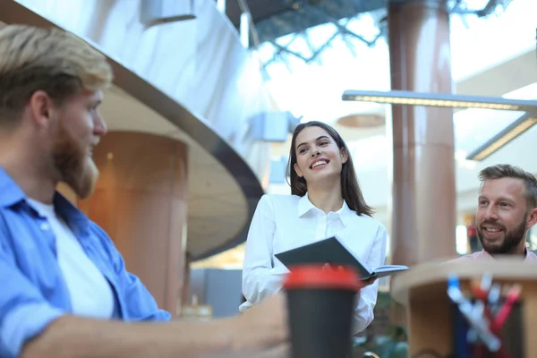 Gruppo di giovani in abbigliamento casual seduti alla scrivania dell'ufficio e discutere di qualcosa mentre guardano il PC insieme . — Foto Stock