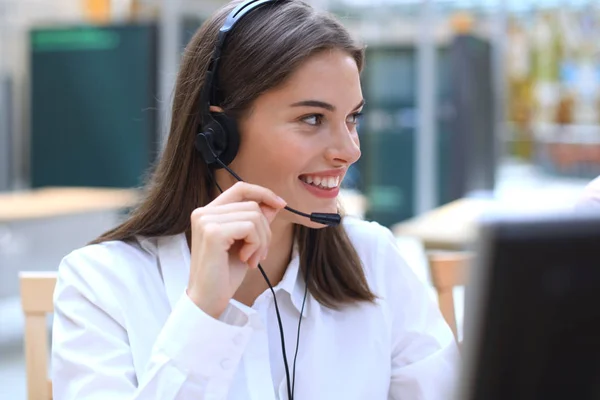 Operadora de suporte ao cliente feminina com fone de ouvido e sorrindo. — Fotografia de Stock