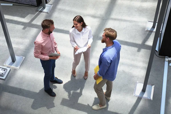 Vue du dessus des jeunes gens modernes en vêtements décontractés intelligents discutant affaires tout en se tenant dans le bureau créatif . — Photo