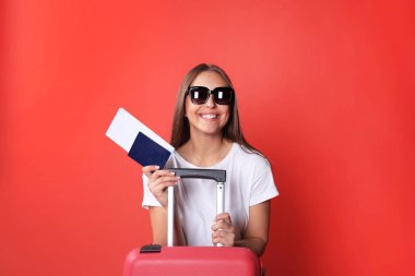 Güneş gözlüğü, kırmızı çanta, kırmızı zemin üzerine izole pasaport ile yaz casual giysili genç turist kızı.