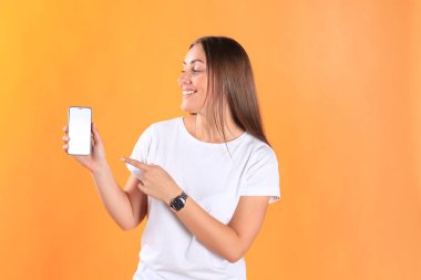 Heyecanlı mutlu sevimli genç kadın cep telefonu görüntüsünü gösterilen tarih izole sarı arka plan poz.