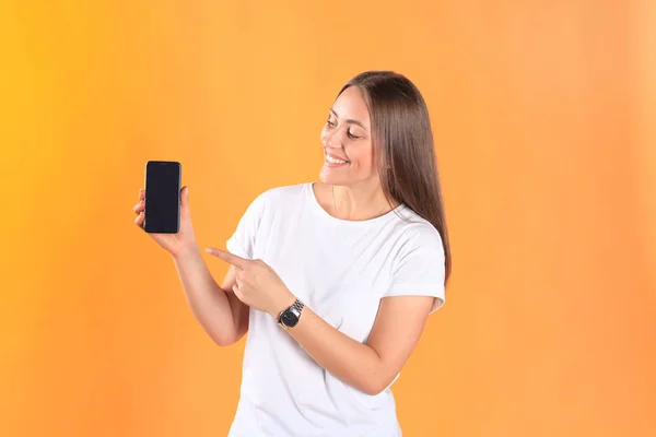 Mujer joven vestida con ropa básica aislada sobre fondo amarillo, usando teléfono móvil . —  Fotos de Stock