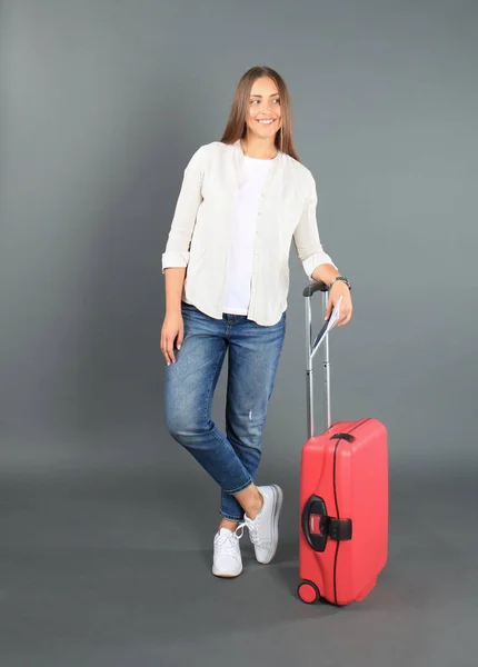 Jeune fille touristique en vêtements décontractés d'été, avec valise rouge, passeport, billets isolés sur fond gris . — Photo