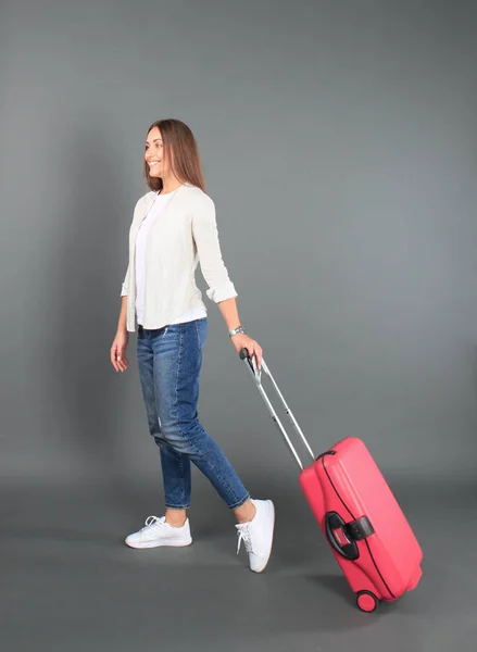 Jeune fille touristique en vêtements décontractés d'été, avec valise rouge, passeport, billets isolés sur fond gris . — Photo