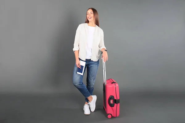 Jeune fille touristique en vêtements décontractés d'été, avec valise rouge, passeport, billets isolés sur fond gris . — Photo