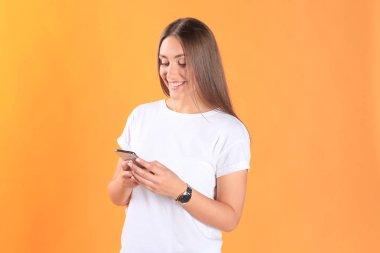 Cep telefonunuzun temel giyim sarı arka plan üzerinde izole giymiş genç kadın.