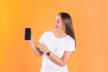 Cep telefonunuzun temel giyim sarı arka plan üzerinde izole giymiş genç kadın.