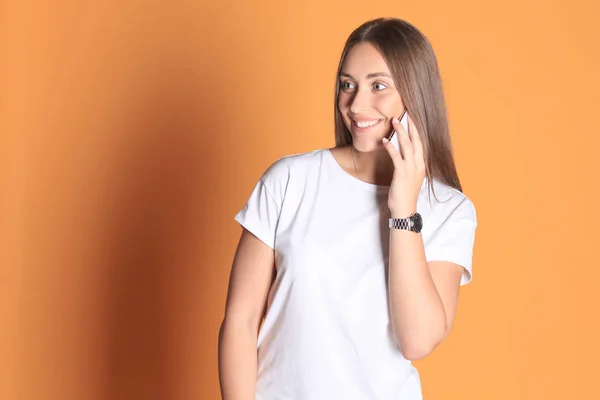 Молодая женщина, одетая в основную одежду изолирована на желтом фоне, разговаривает по мобильному телефону . — стоковое фото