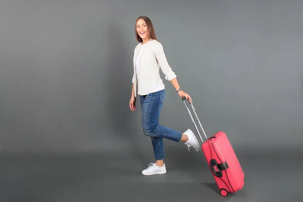 Jeune fille touristique en vêtements décontractés d'été, avec valise rouge, passeport, billets isolés sur fond gris . — Photo