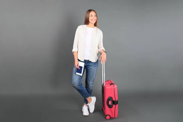 Jeune fille touristique en vêtements décontractés d'été, avec valise rouge, passeport, billets isolés sur fond gris . — Photo