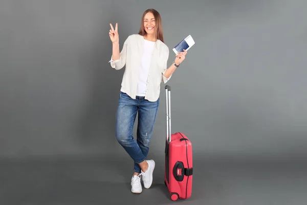 Giovane turista in abiti casual estivi, con valigia rossa, passaporto, biglietti isolati su sfondo grigio . — Foto Stock