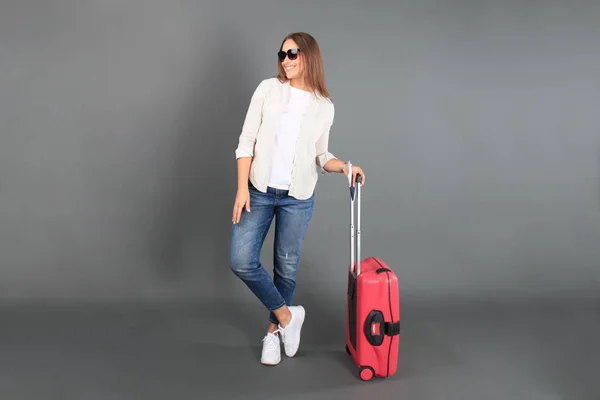 Genç turist kız yaz rahat giysileri, güneş gözlüğü, kırmızı çanta, pasaport, Bilet gri arka plan izole.. — Stok fotoğraf