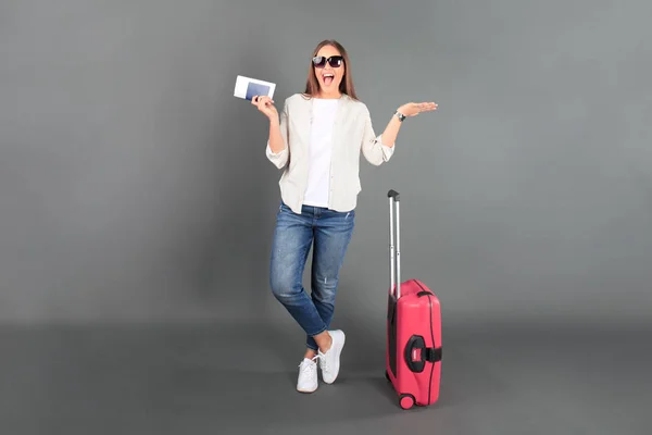 Gadis wisatawan muda dengan pakaian santai musim panas, dengan kacamata hitam, koper merah, paspor, tiket terisolasi latar belakang abu-abu . — Stok Foto