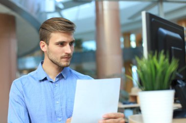 genç işadamı masasında Office belgeleri okuma.