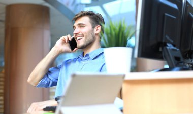 Oturma ve cep telefonu kullanma office işadamı gülümseyen.