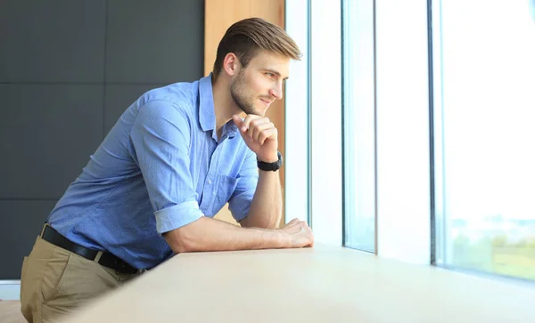 Fiatal férfi az irodájában, miközben gondolkodás céljait ablak közelében. — Stock Fotó