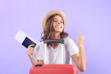 Güneş gözlüğü, kırmızı çanta, mor arka plan üzerinde izole pasaport ile yaz casual giysili genç turist kızı.