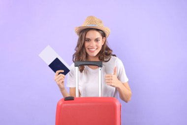 Güneş gözlüğü, kırmızı çanta, mor arka plan üzerinde izole pasaport ile yaz casual giysili genç turist kızı.