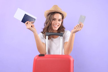 Güneş gözlüğü, kırmızı çanta, mor arka plan üzerinde izole pasaport ile plastik kredi kartı gösteren turist kız.