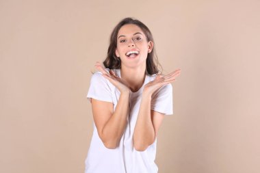 Genç kadın merak ve bej renkli arka plan üzerinde izole çığlık casual giyim.