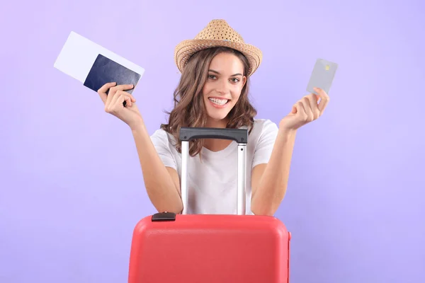 Fille touristique en montrant carte de crédit en plastique avec des lunettes de soleil, valise rouge, passeport isolé sur fond violet . — Photo