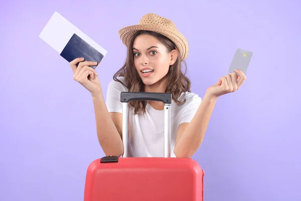 Toeristische meisje aan te tonen van kunststof creditcard met zonnebril, rode koffer, paspoort geïsoleerd op paarse achtergrond. — Stockfoto