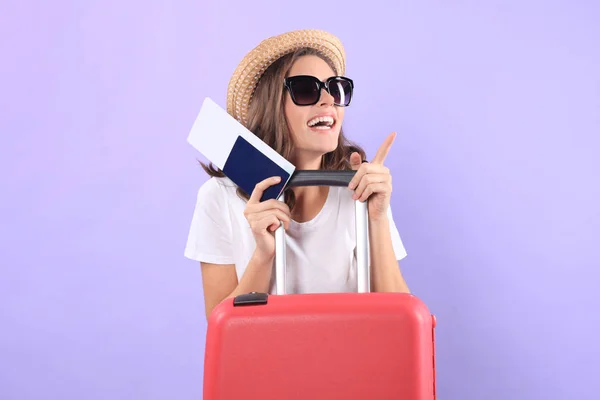 Gadis wisatawan muda dengan pakaian santai musim panas, dengan kacamata hitam, koper merah, paspor terisolasi di latar belakang ungu . — Stok Foto