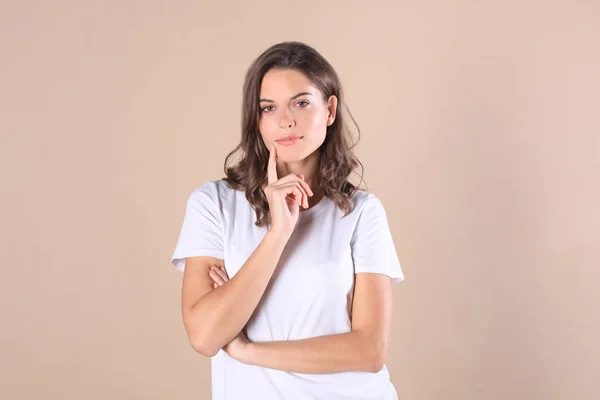 Mulher morena alegre vestida com roupas básicas olhando para a câmera, isolada no fundo bege . — Fotografia de Stock