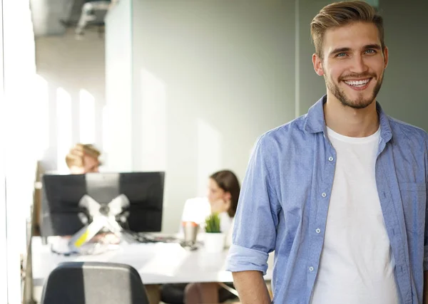 Retrato de un joven y feliz hombre de negocios casual en la oficina, sonriendo . — Foto de Stock