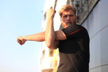 Açık havada duran süre çalıştırmadan önce germe yapan yakışıklı genç erkek egzersizleri.
