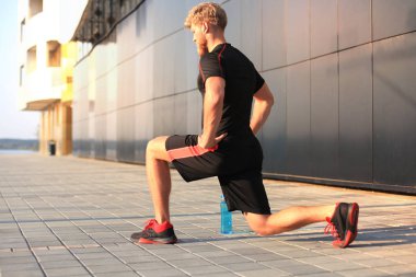 Açık havada duran süre çalıştırmadan önce germe yapan yakışıklı genç erkek egzersizleri.