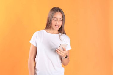 Cep telefonunuzun temel giyim sarı arka plan üzerinde izole giymiş genç kadın.
