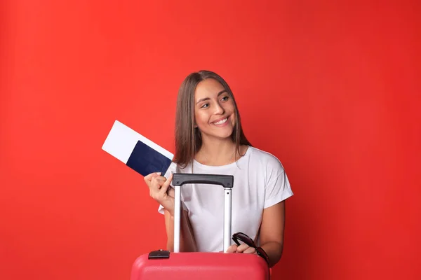 Menina turística jovem em roupas casuais de verão, com óculos de sol, mala vermelha, passaporte isolado no fundo vermelho . — Fotografia de Stock