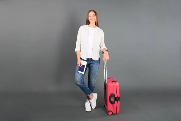 Jeune fille touristique en vêtements décontractés d'été, avec valise rouge, passeport, billets isolés sur fond gris . — Photo