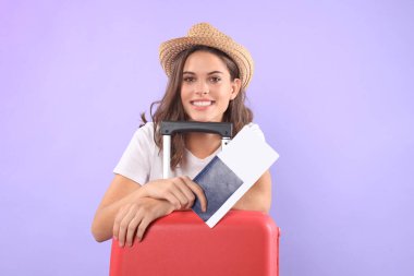 Güneş gözlüğü, kırmızı çanta, mor arka plan üzerinde izole pasaport ile yaz casual giysili genç turist kızı.